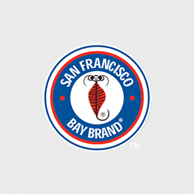 A circular logo with San Francisco Bay Brand in blue text on a white background, featuring a red striped shrimp illustration in the center, all bordered by blue and red rings.